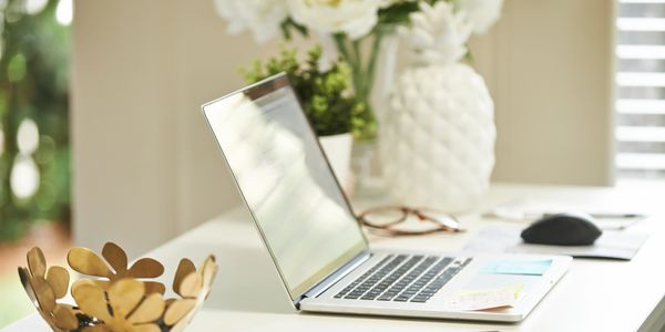 A clean workspace with a laptop, smartphone, and decorative items.