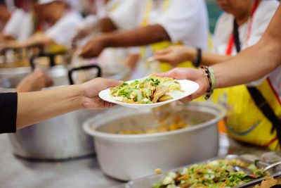 Person serving food on a plate at a community food line.