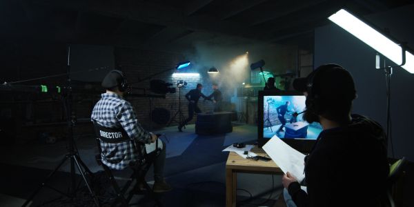 Film director and crew filming an indoor action scene.
