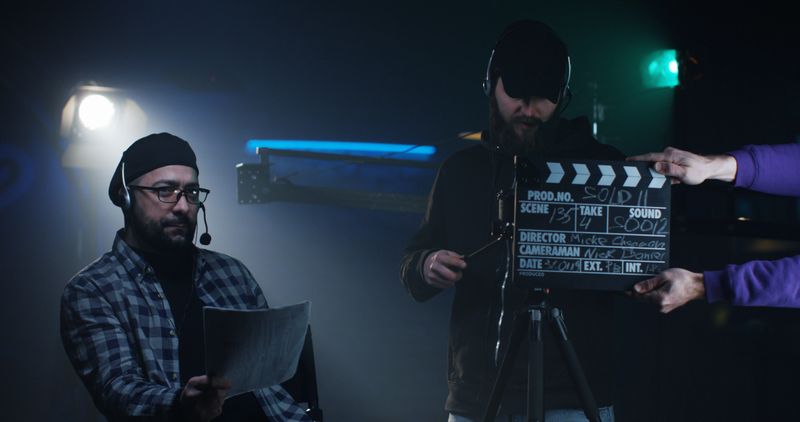 Medium shot of a young director giving instructions on a film set while cameraman filming