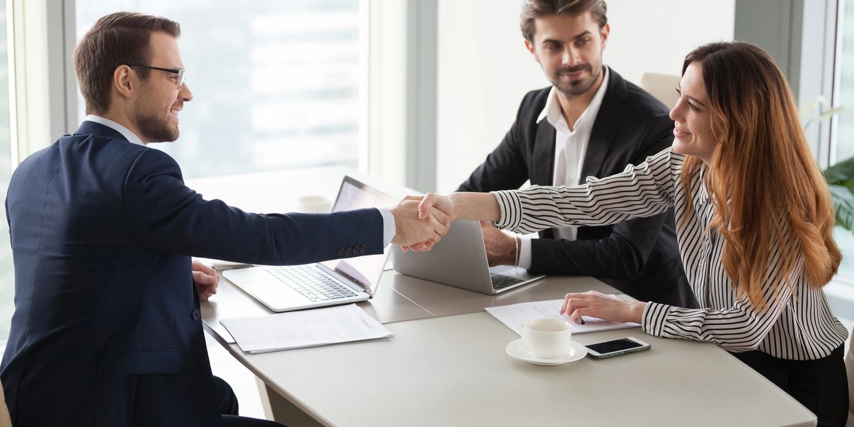 Business professionals shaking hands during a meeting in a modern office.