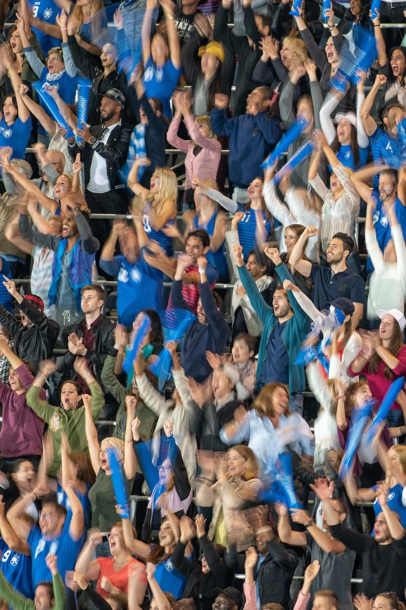 Blurred motion of group of football fans cheering while watching match in stadium.