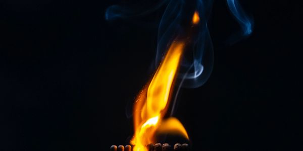 Bright flame and smoke rising from a row of burning matches.