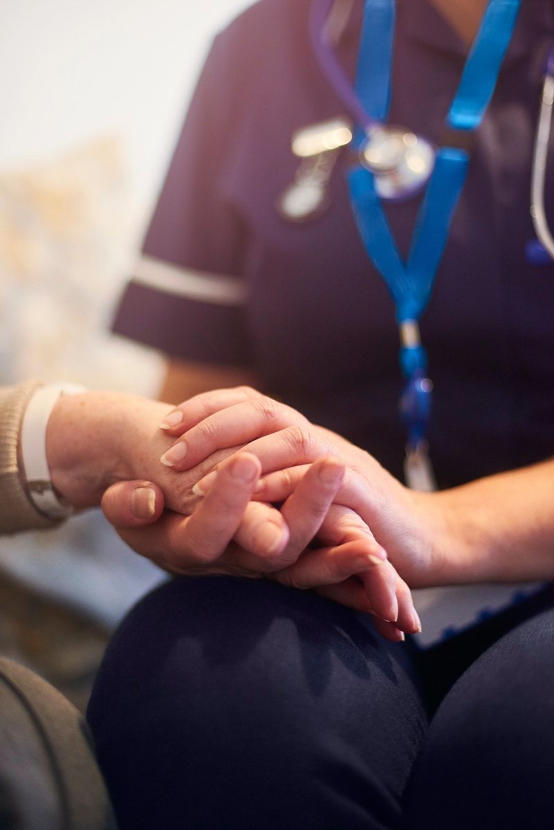 A female nurse consoles a senior patient at home