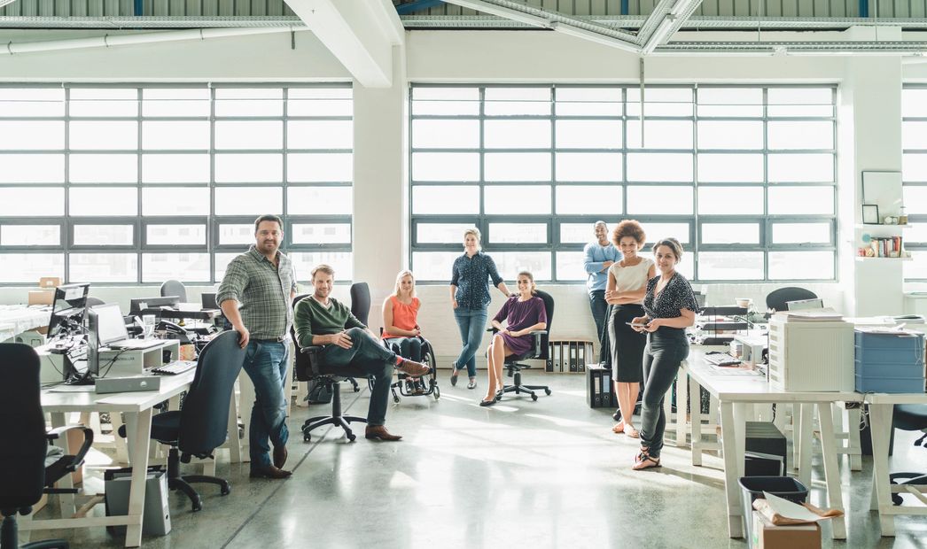 Diverse group of coworkers posing in a bright, modern office space.