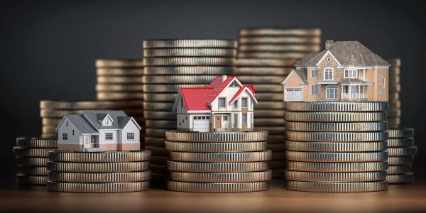 Miniature houses on stacks of coins symbolizing real estate investment.