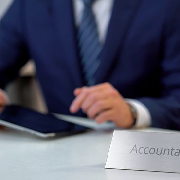 Professional accountant in a suit using a tablet at desk.