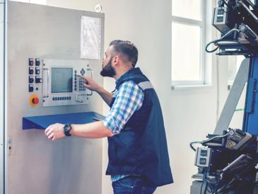Man operating a control panel in an industrial setting.