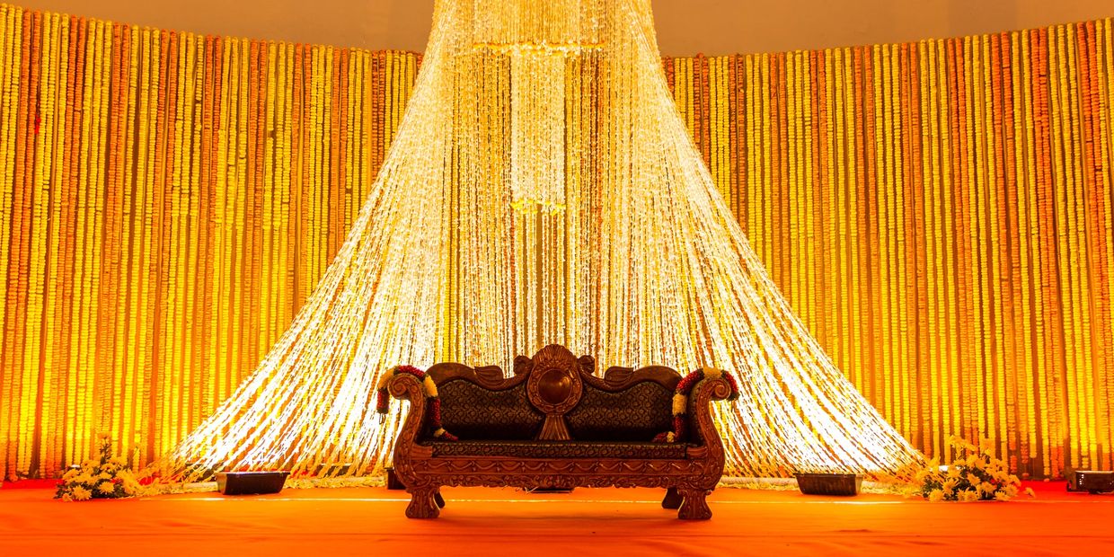 Ornate sofa against a bright floral backdrop with cascading garlands.