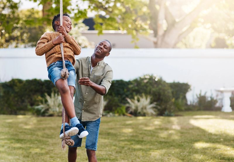 Shot of a father and his little son playing on a rope swing outdoors