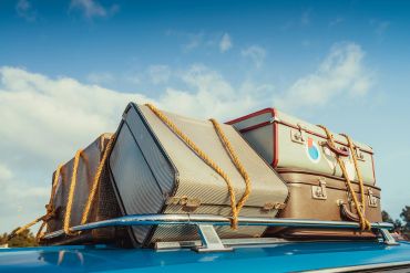 Suitcases tied on top of a car roof rack.