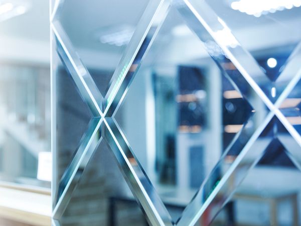 Close-up of a glass panel with diamond-shaped patterns reflecting a modern interior.