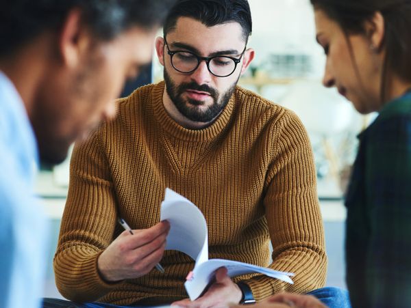 Man in glasses reviewing documents with two colleagues.
