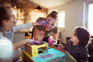 Children and woman having fun painting together indoors.