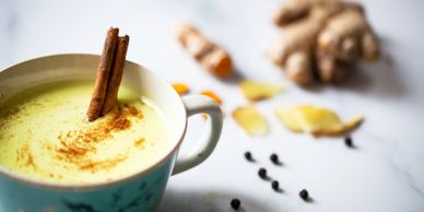 Cup of turmeric latte with cinnamon sticks and spices.