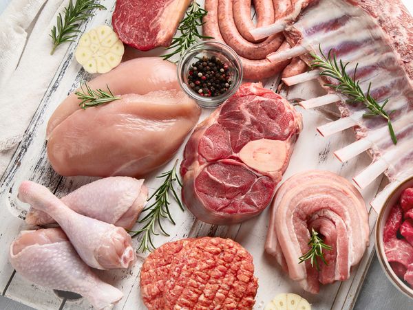 Various raw meats and herbs arranged on wooden boards.