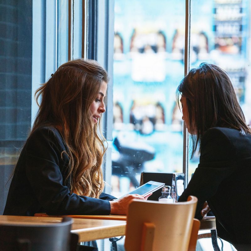 Two businesswomen using tablet in meeting, business communication connection people concept