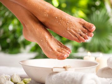 Feet being pampered in a spa setting with a bowl and towels.