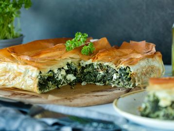 A slice of spinach and feta pie with golden flaky crust.
