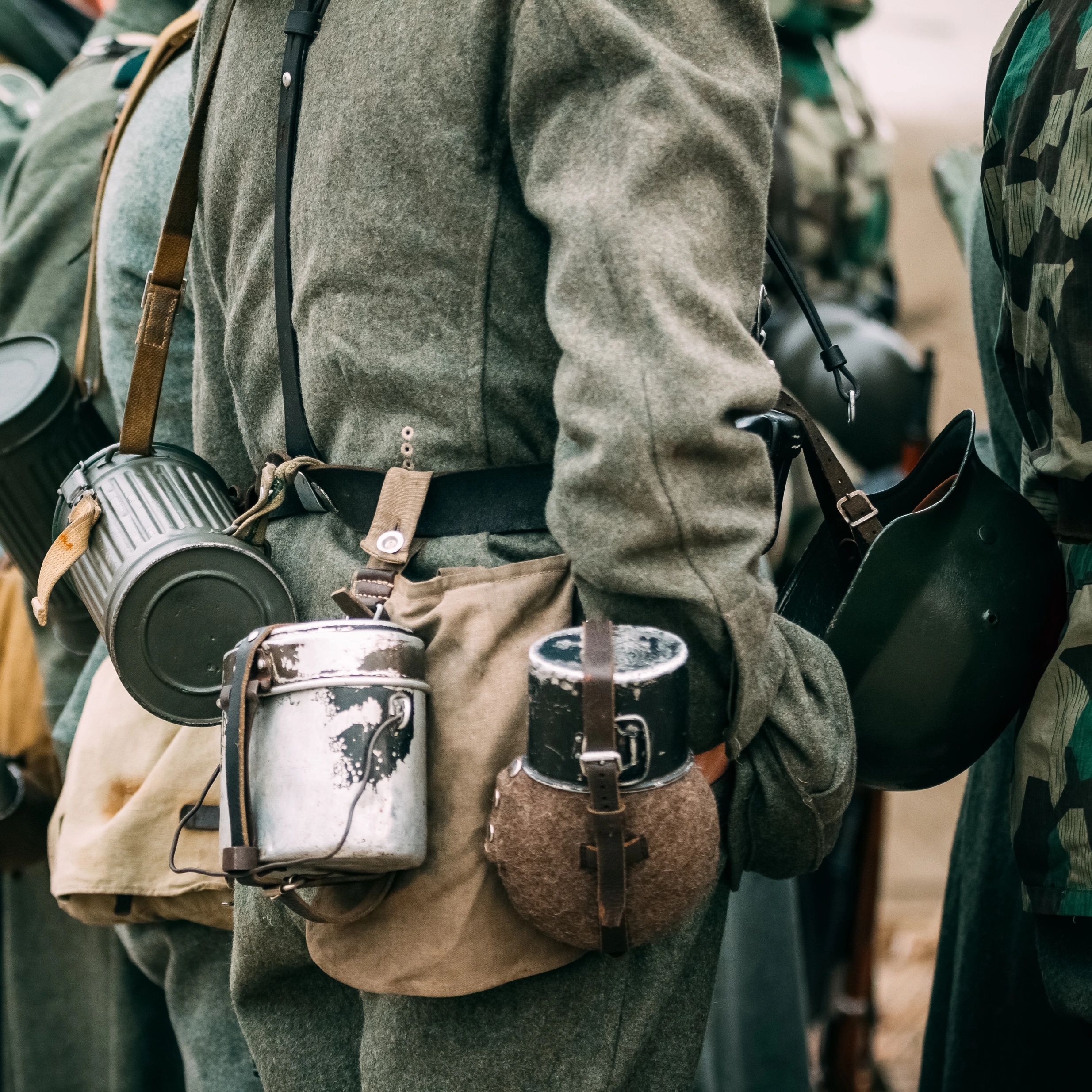 Close-up of soldiers in vintage military uniforms carrying canteens and gear.