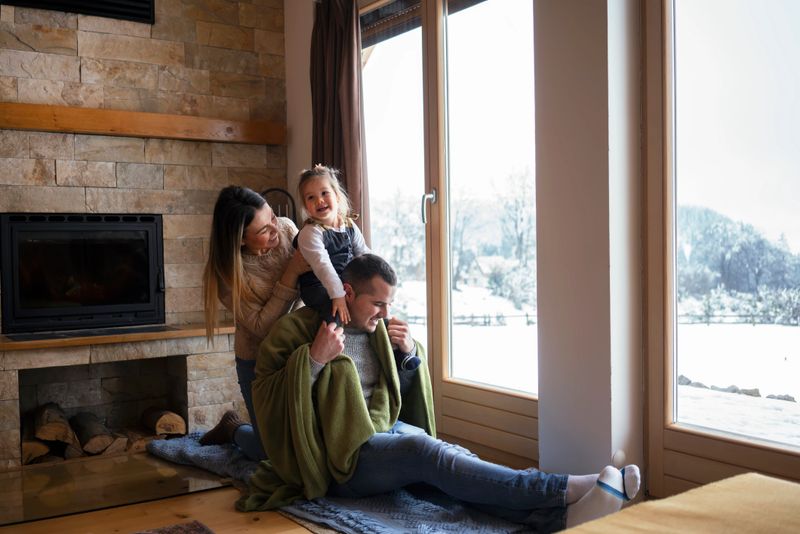 Young family on winter vacation, looking through window