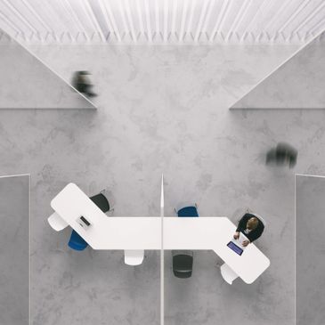 Top-down view of a modern office with a white desk and people working.