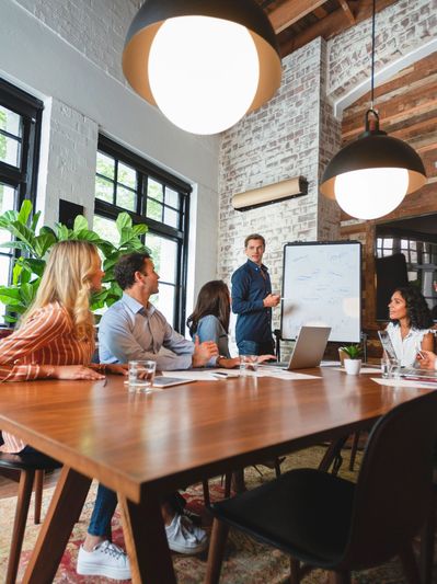 Team meeting with a presenter at a whiteboard in a stylish office.