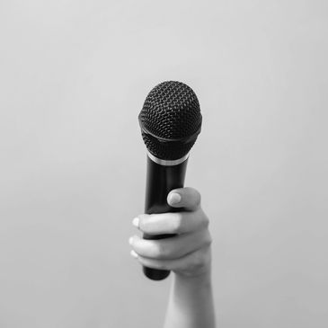 Hand holding a microphone against a plain background.