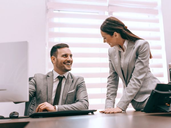 Two business professionals smiling and interacting in an office.