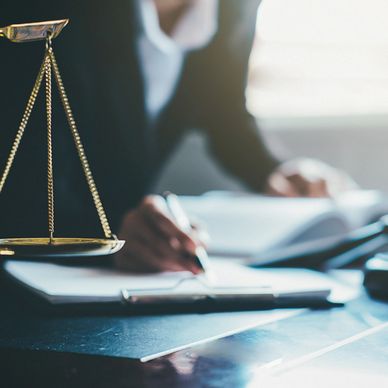 A lawyer working with legal documents and scales of justice on the desk.