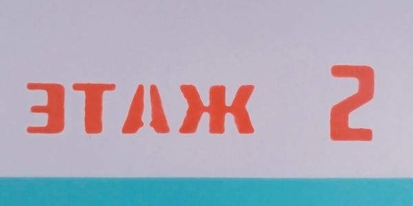 Reversed red text on a wall with a blue stripe below.