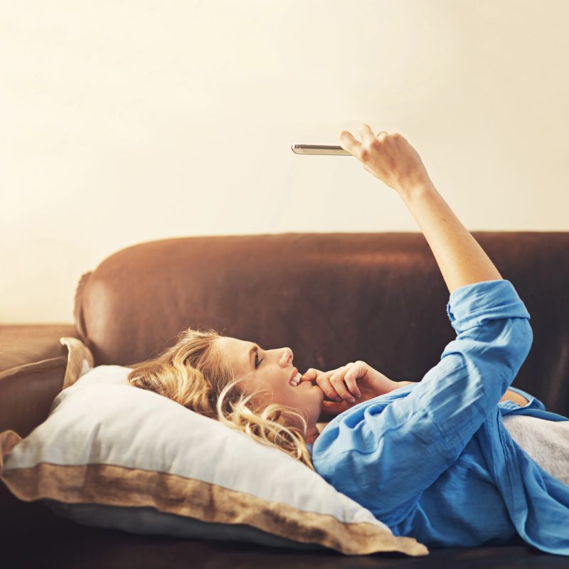 Shot of a relaxed young woman using a smartphone on the sofa at home