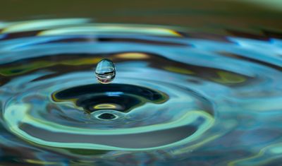 an image of water with a droplet landing in it, creating a ripple