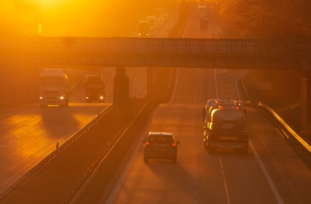 Highway traffic during a golden sunset with trucks and cars.