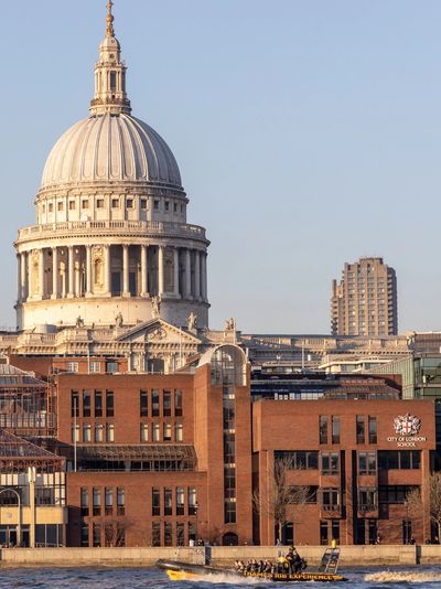 St. Paul's Cathedral with a boat on the Thames River in London at sunset.