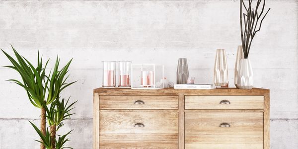 Rustic wooden dresser with decorative vases and candles against a textured white wall.