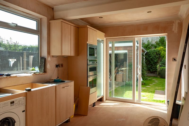 Scene inside a house undergoing a kitchen refurbishment after the cabinets are partially fitted and the appliances installed.