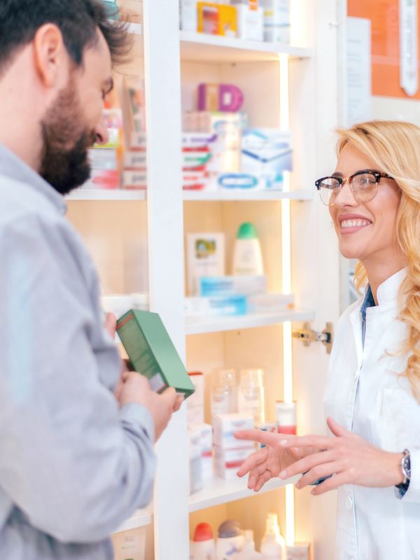Pharmacist assisting a customer in a pharmacy with a smile.