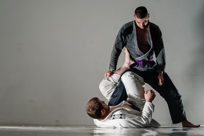 Two men practicing Brazilian jiu-jitsu in gis indoors.