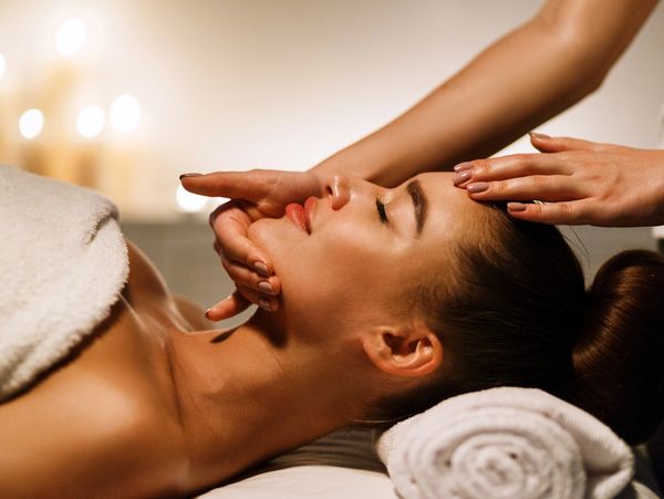 Woman receiving a relaxing facial massage in a spa setting.