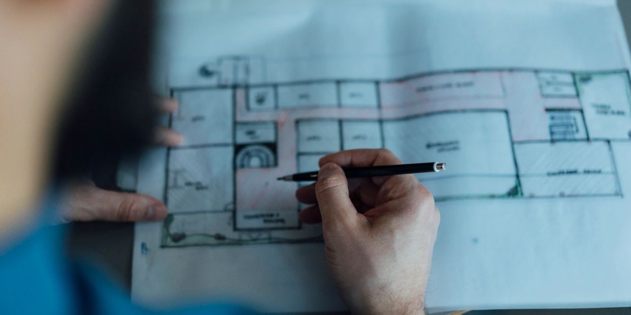 Hand sketching a floor plan with a pencil.