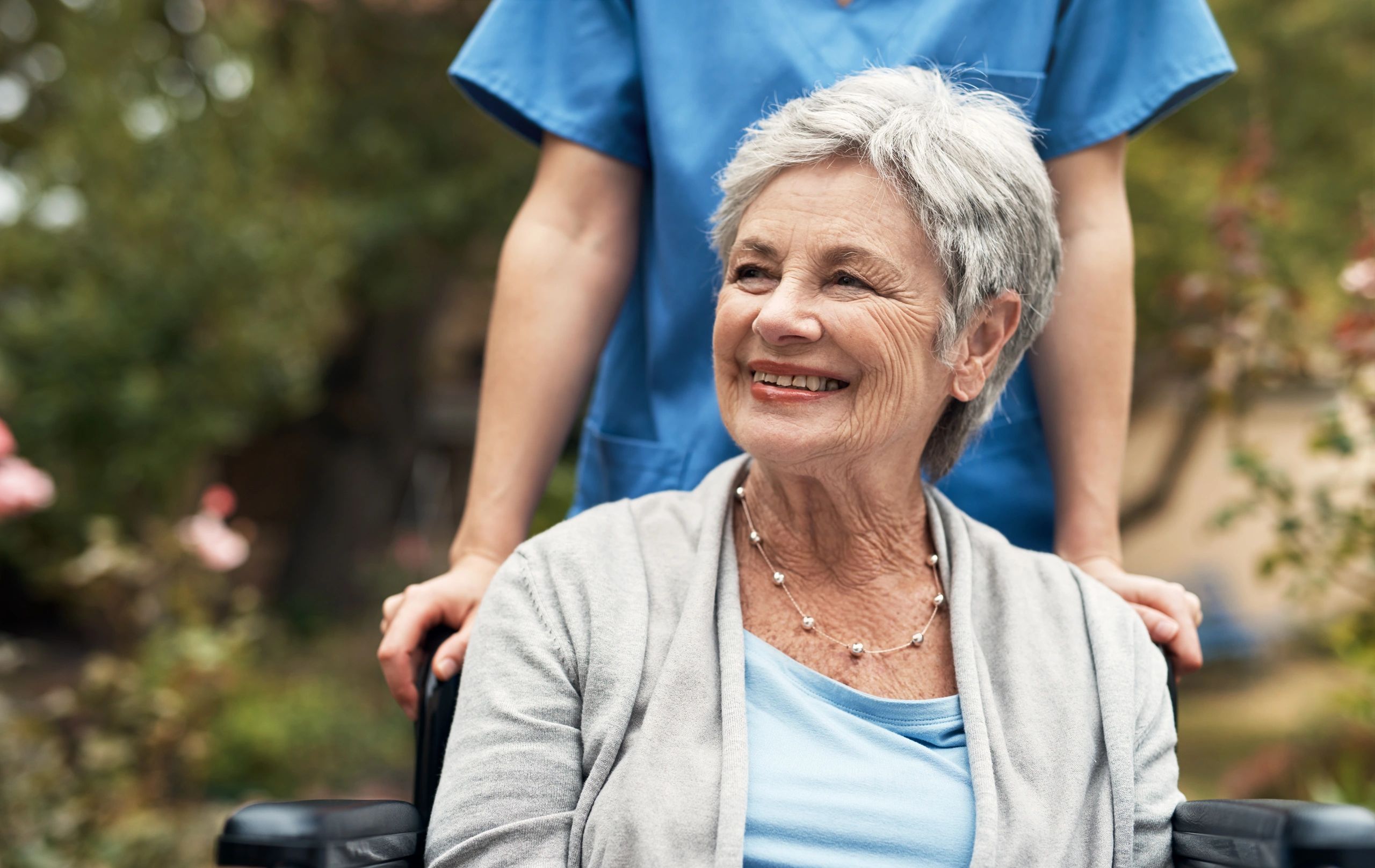 Senior woman smiling in wheelchair with a nurse.