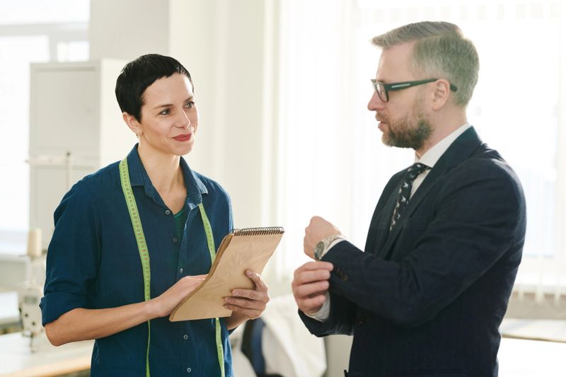 Happy female tailor having conversation with one of clients