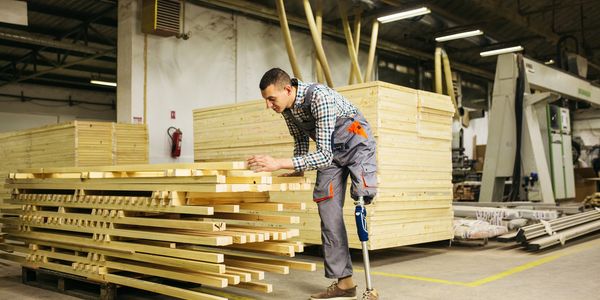 Man with prosthetic leg working with a stack of wood.