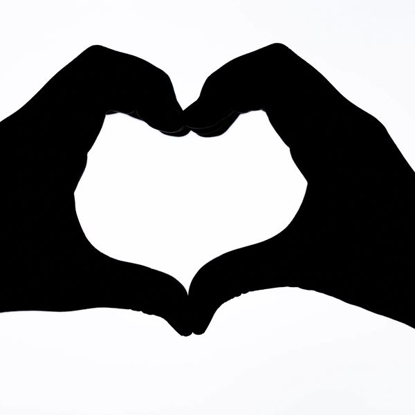 Silhouette of hands forming a heart shape against a white background.