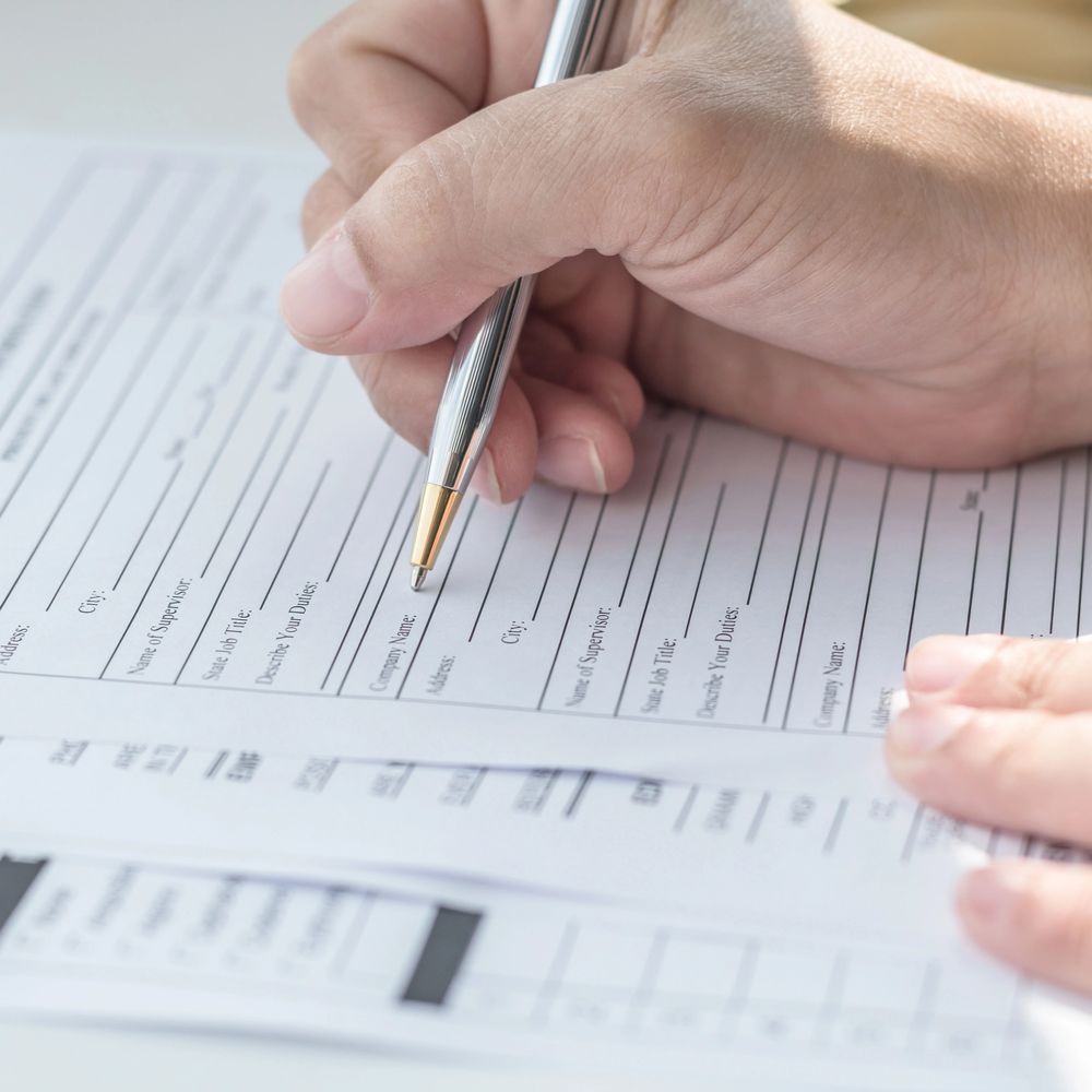 Person filling out a detailed form with a pen.