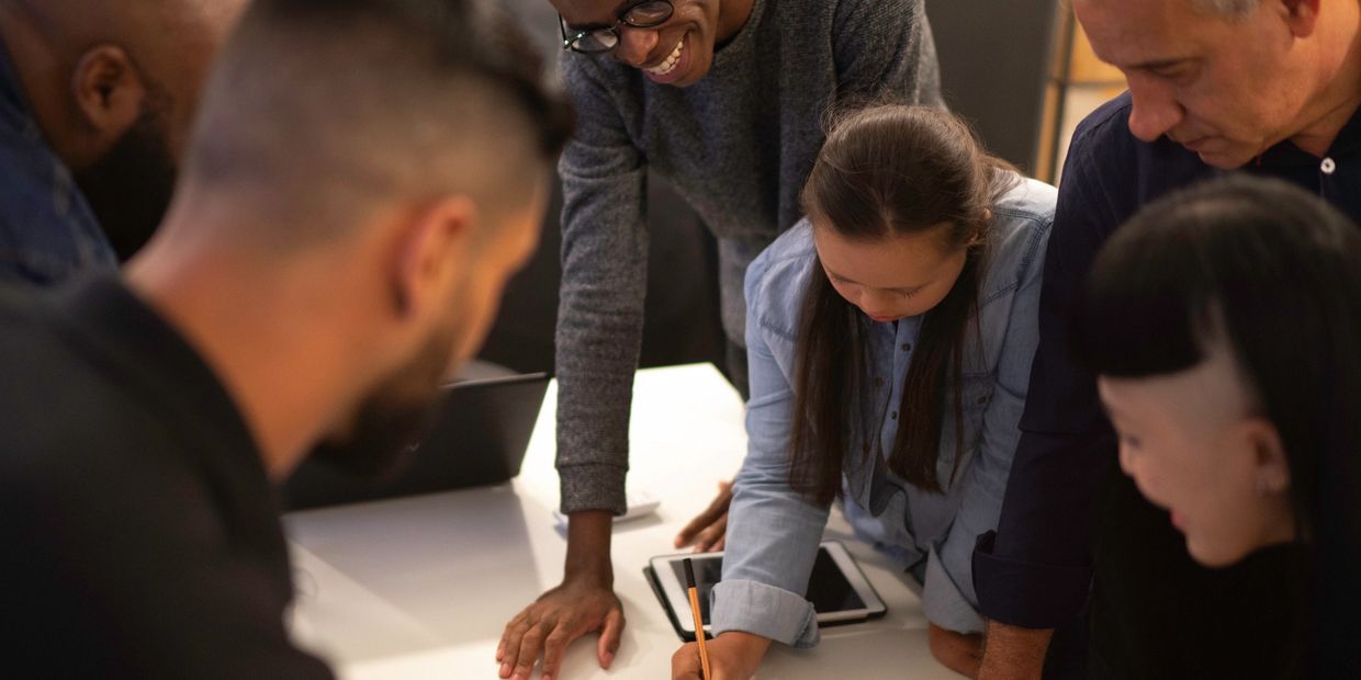 A diverse group collaborates on a project around a table.