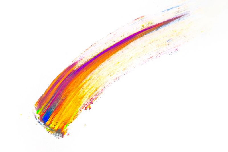 Abstract smear made of multicolored pigment, isolated on white. Mixed bright eye shadow predominantly  orange. Natural colored powder.