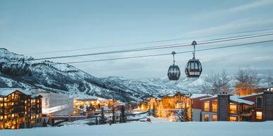 Snowy mountain village with ski gondolas at dusk.