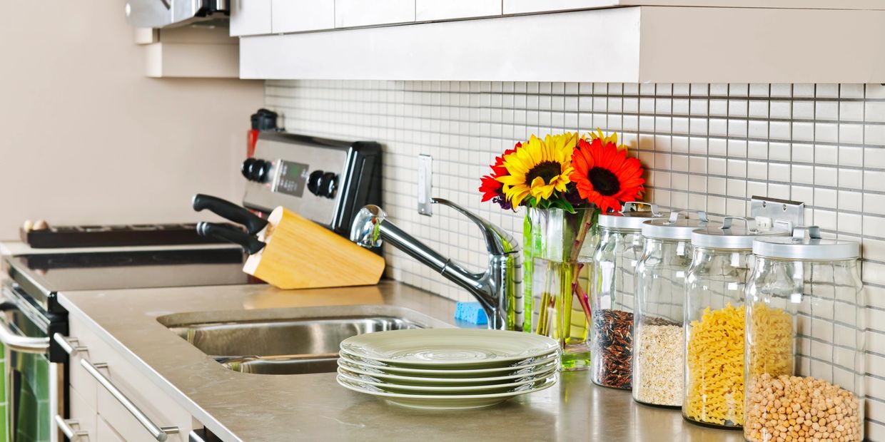 Organized kitchen countertop with jars, plates, and flowers.